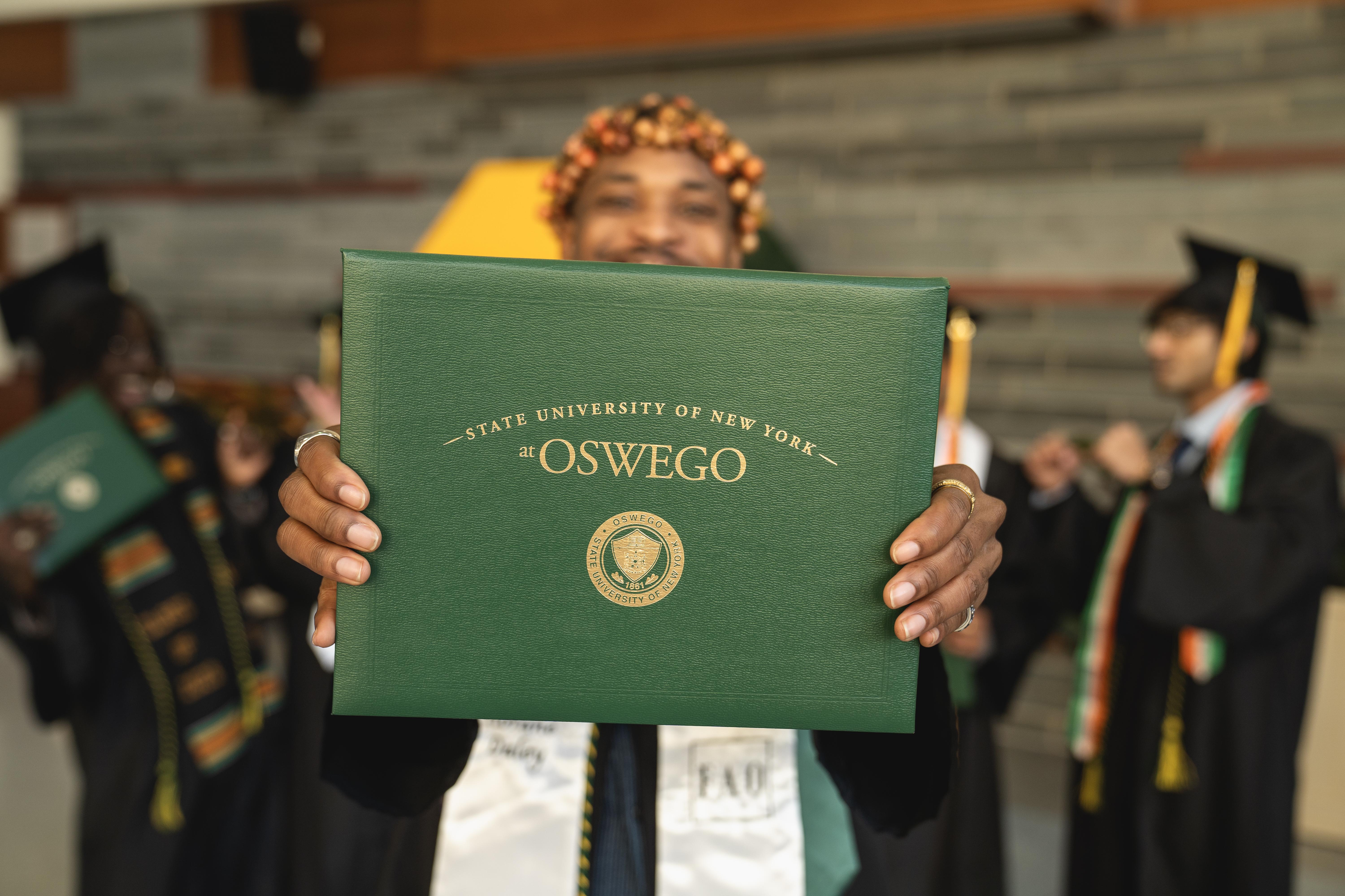 student holding up a diploma in front of other graduates