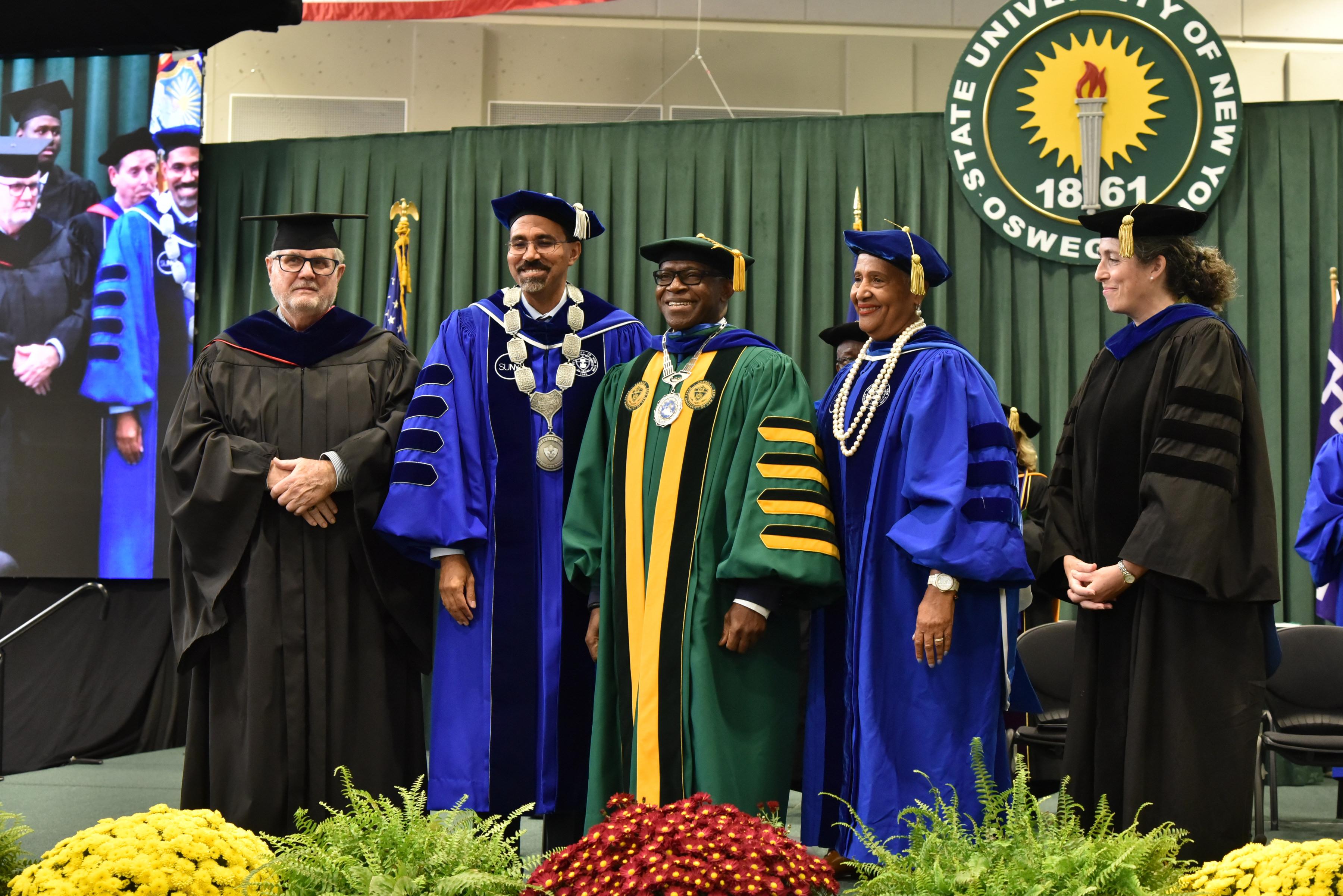 SUNY Oswego’s 11th President Peter O. Nwosu (center) with the ceremonial hood and medallion, with participants (from left) SUNY College Council Chair Jim McMahon, SUNY Chancellor John B. King Jr., SUNY Trustee Eunice Lewin, Faculty Assembly Chair Gwen Kay