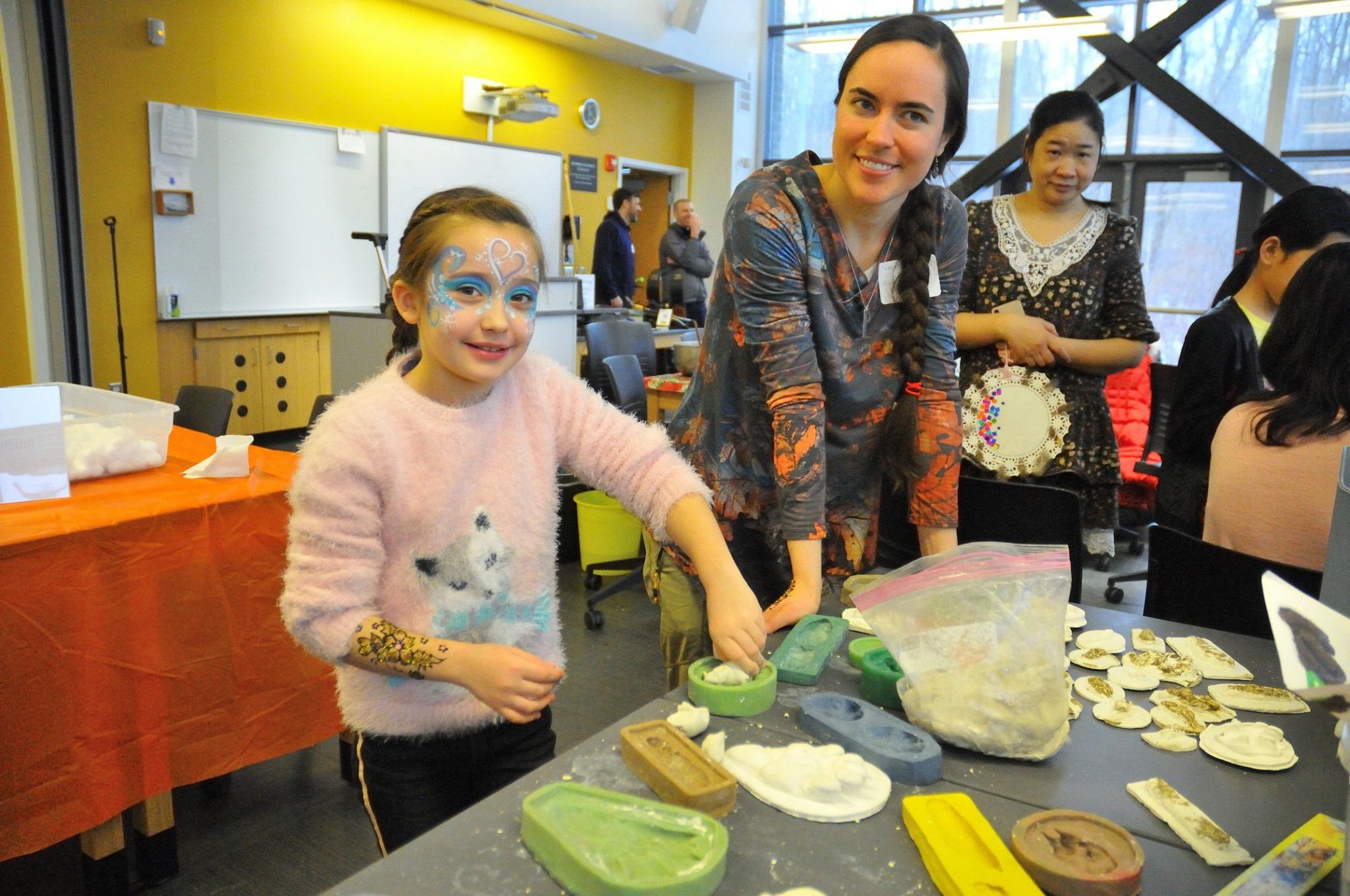 Rice Creek visitor Lexie Prosser works with the field station's Kristen Hansen to make clay animal tracks at a preview Celebrate Snow