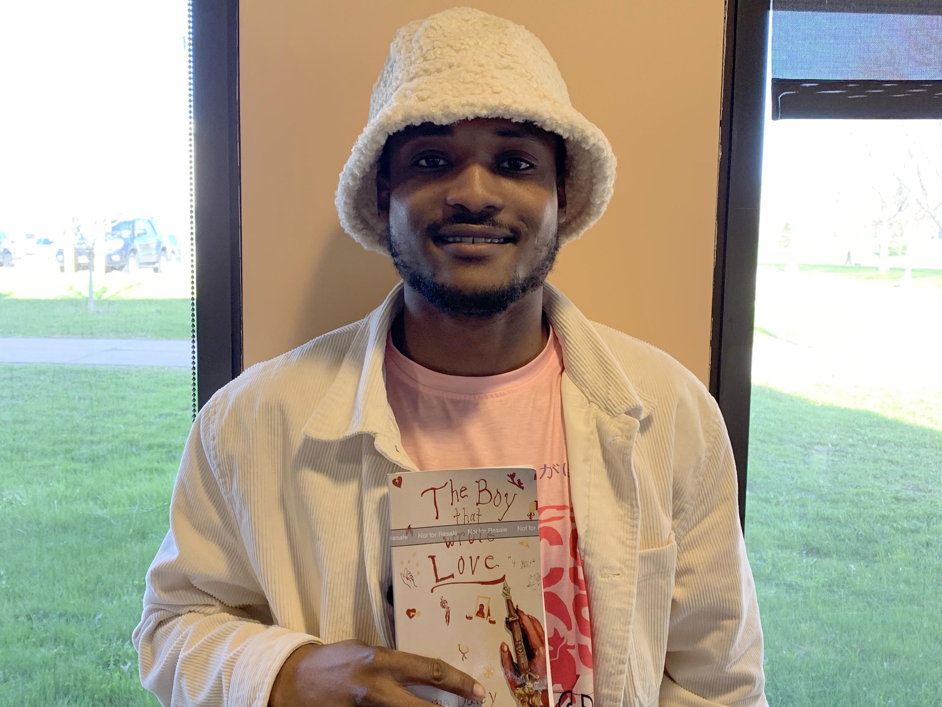 Student Horane Daley holds a copy of his book, The Boy That Wrote Love