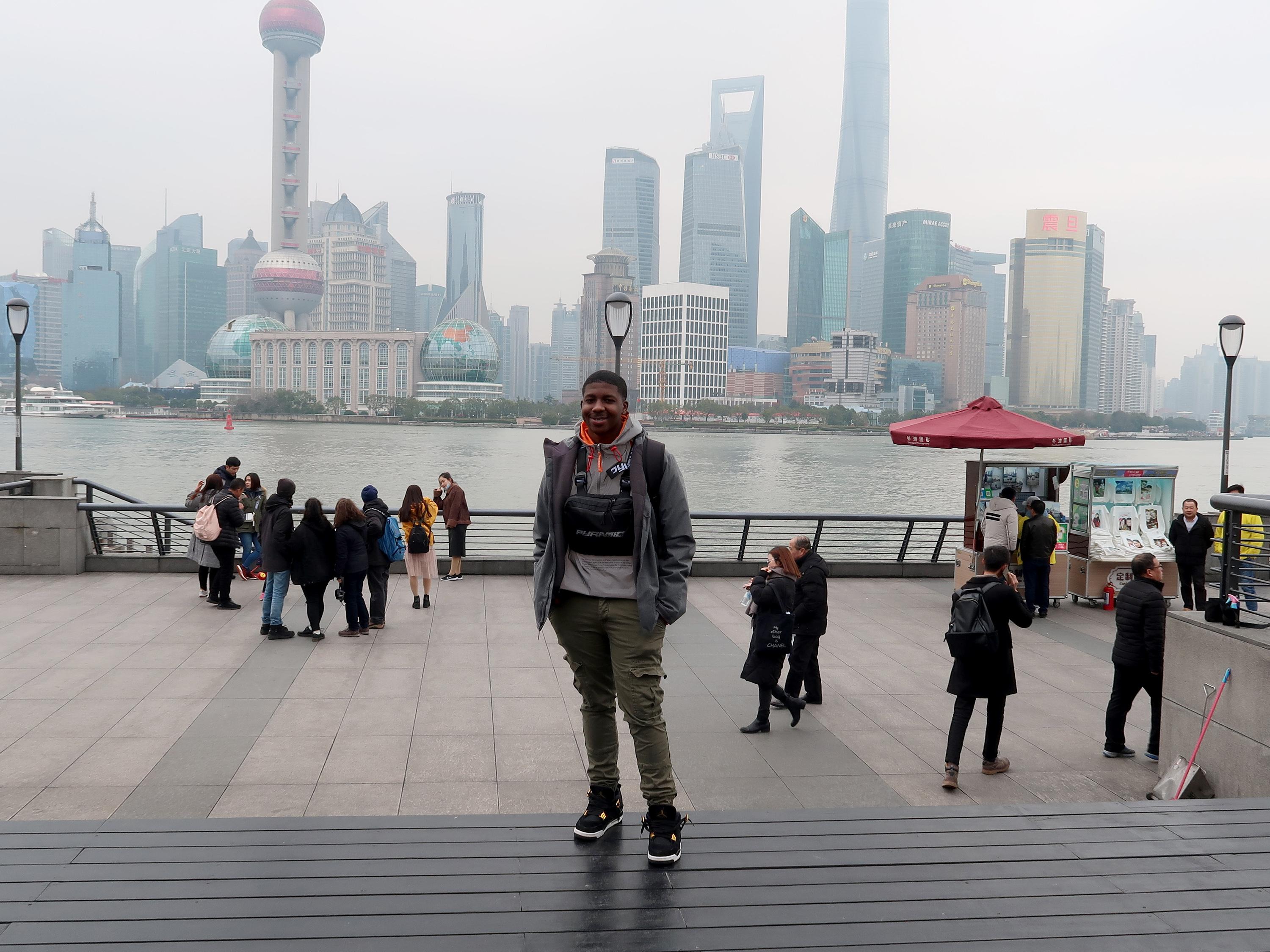 Diandre Coote-Anderson, senior finance major who studied abroad in Shanghai, China, stands in front of a modern cityscape