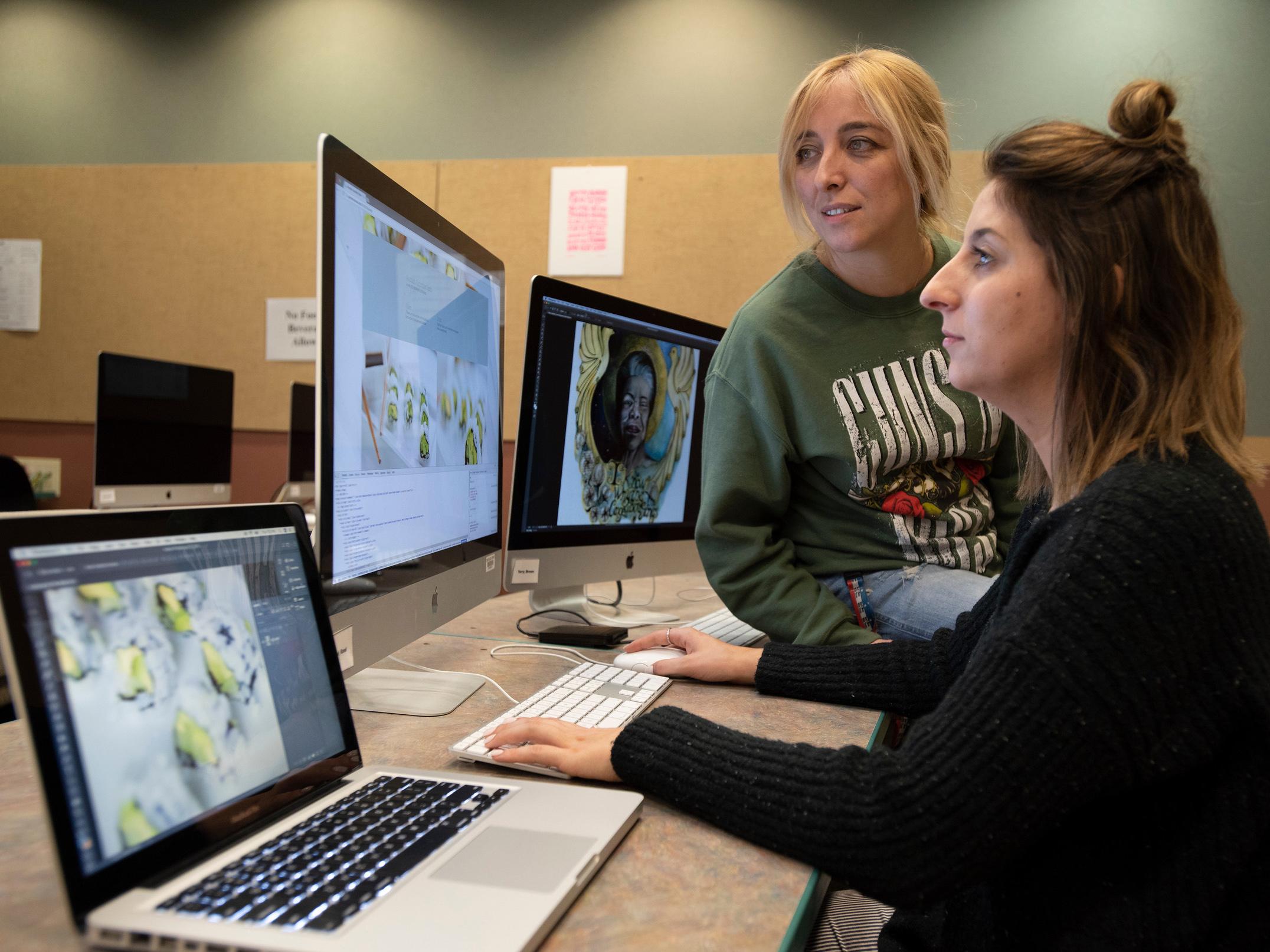 Two students work on digital images in a graphic design lab