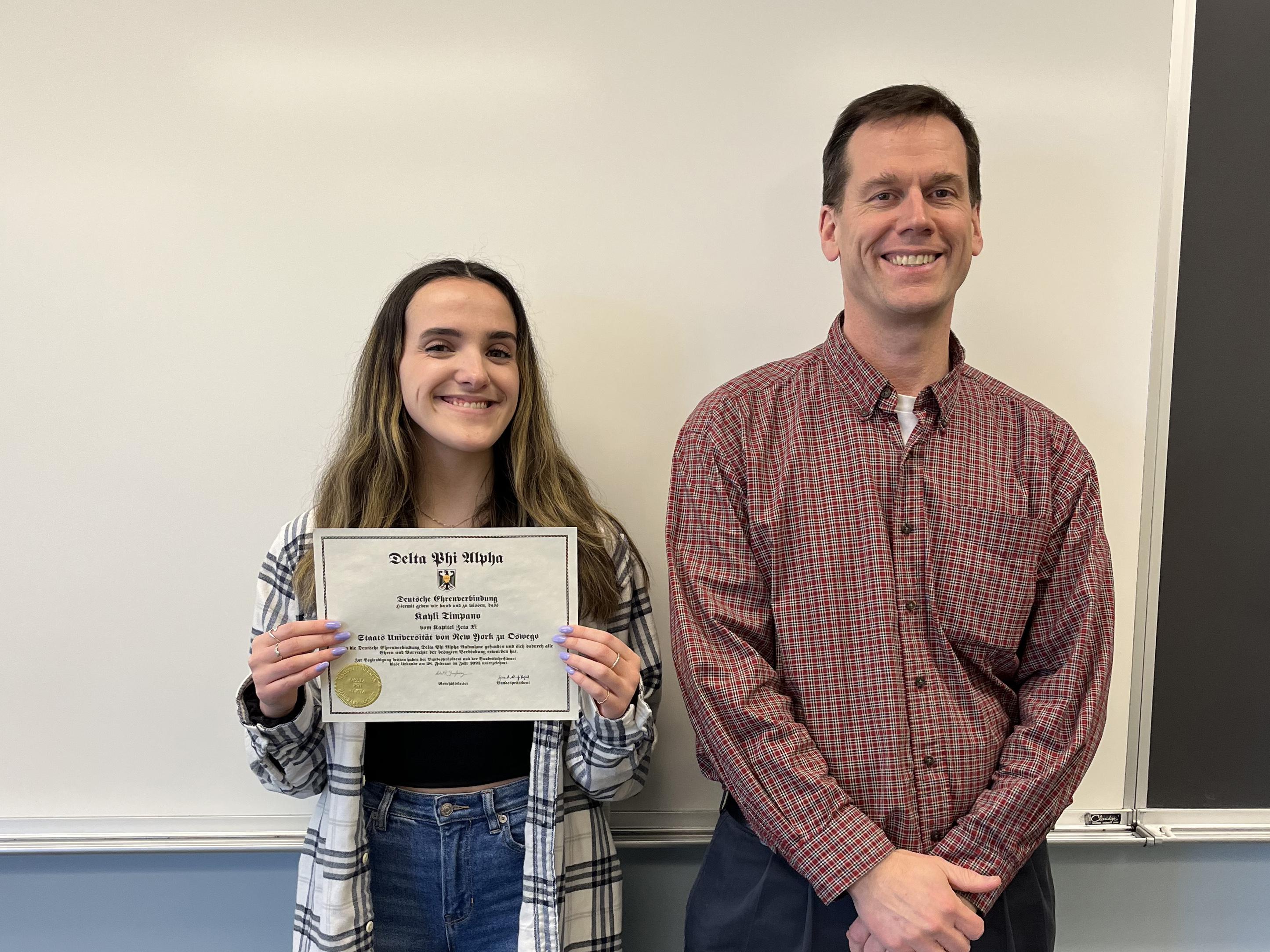 Student Kayli Timpano, here congratulated by modern languages and literatures faculty member Patrick Schultz, earned induction into the SUNY Oswego chapter of Delta Phi Alpha, the National German Honor Society