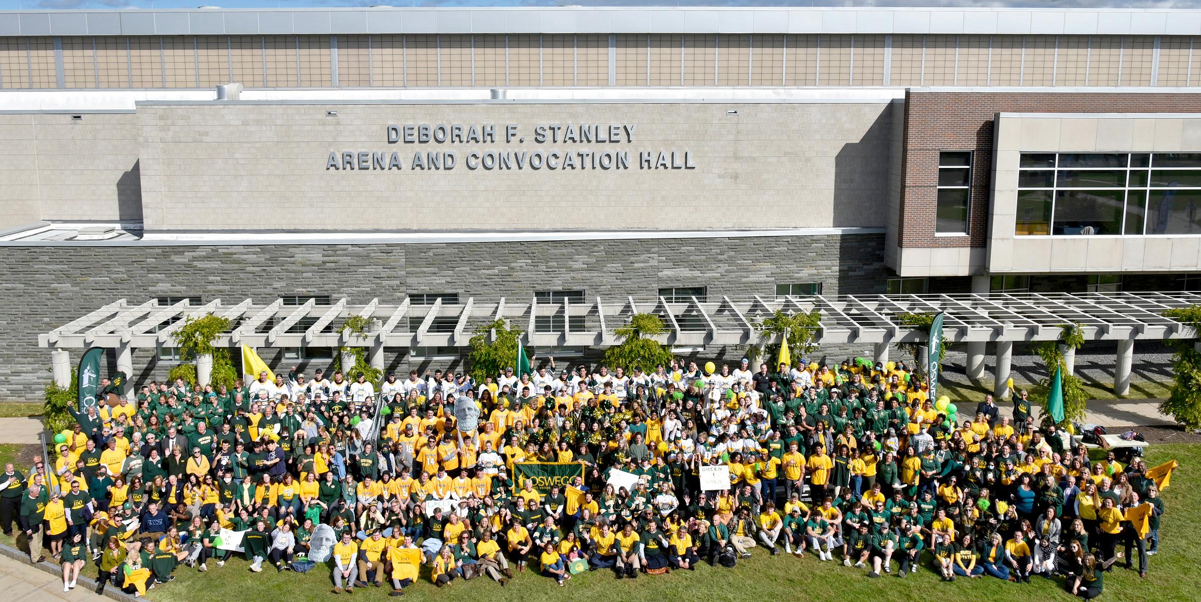 Many members of the Oswego family pose in front of the new sign for the Deborah F. Stanley arena and convocation hall for the 2021 Green and Gold Day photo