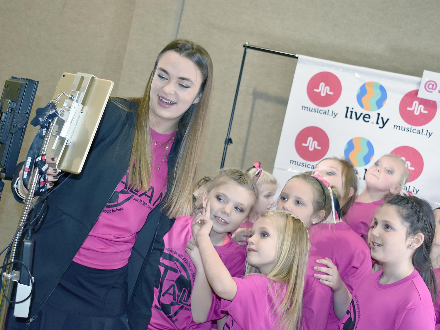 Joely Rice with a group of girls wearing pink shirts for a photoshoot show