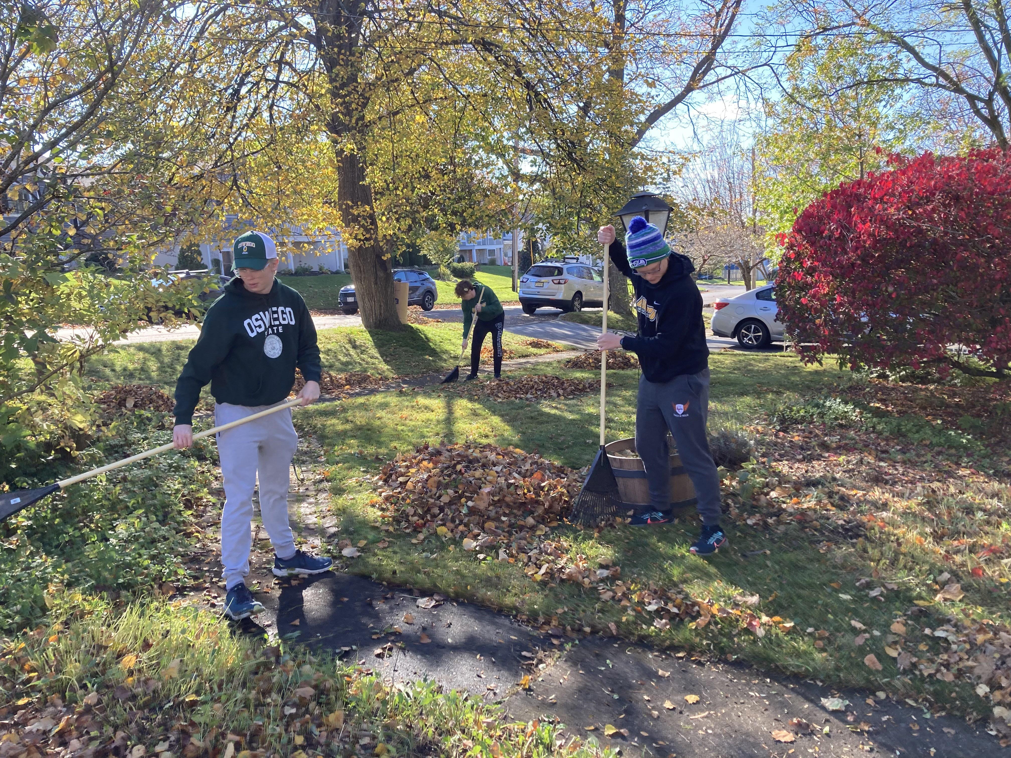 Track and field athletes rake a lawn in the community