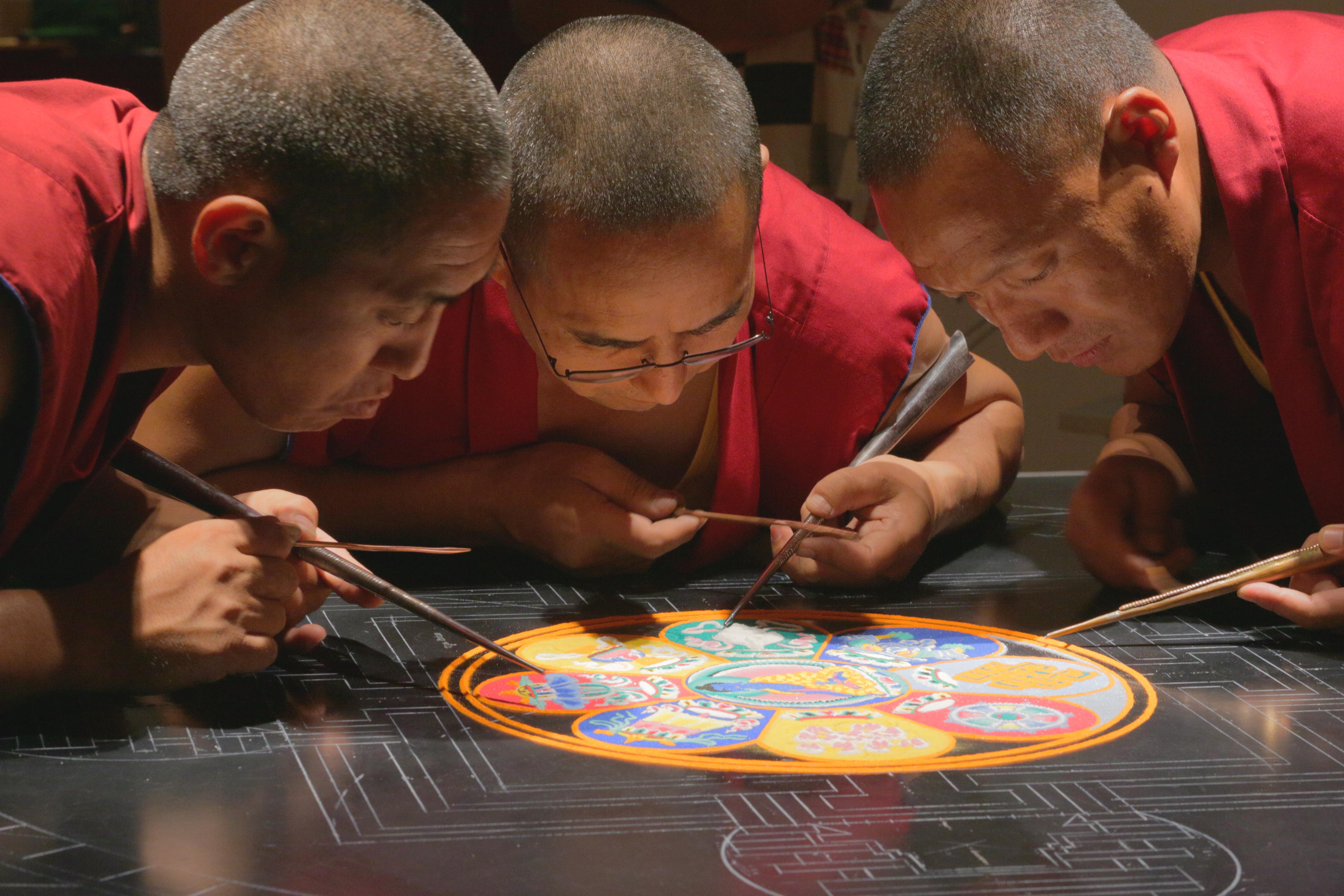 Monks work on creating mandala, beautiful sand art