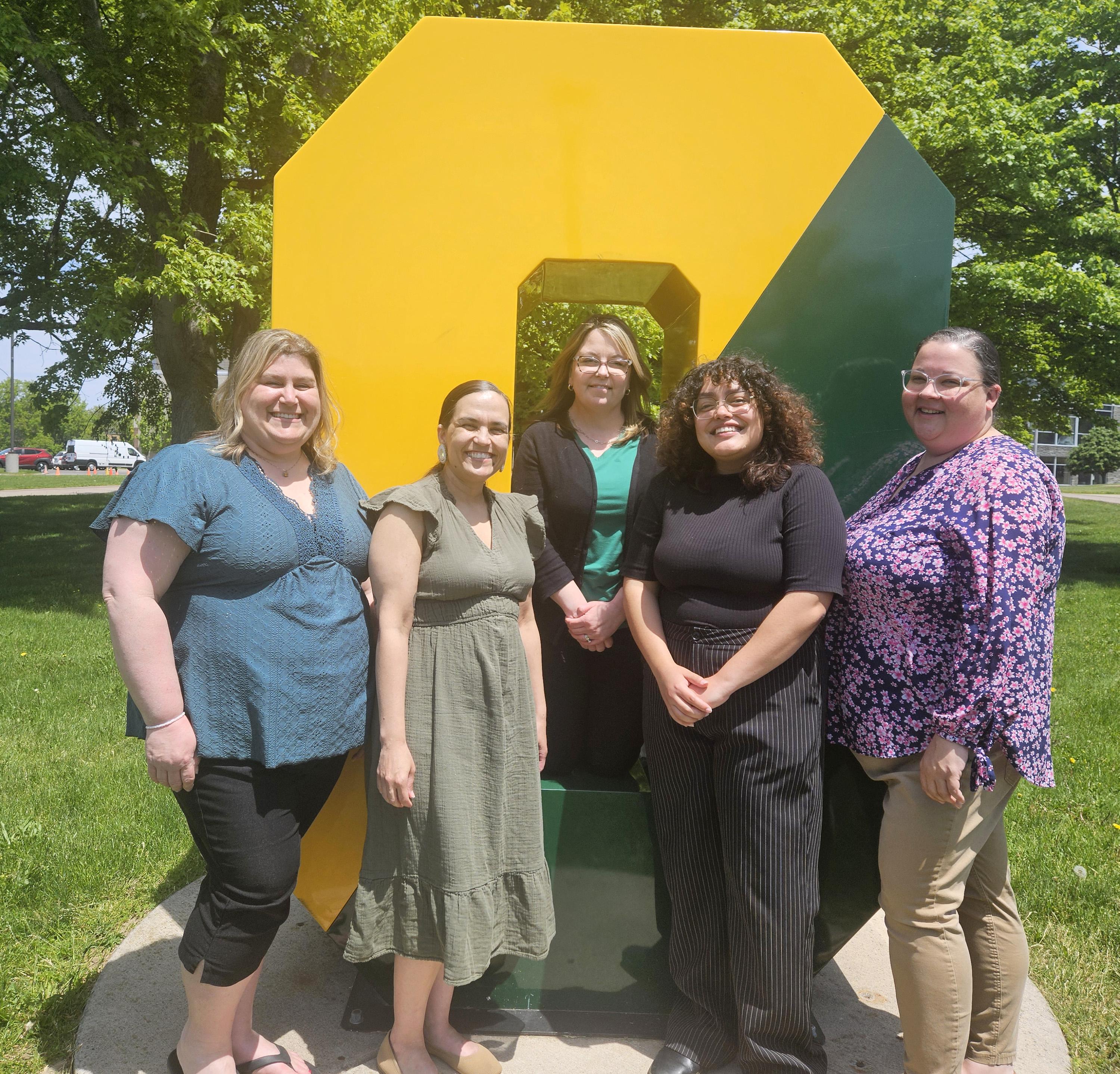 Members of the new Office of Student Wellbeing and Care gather around the Spirit O on campus