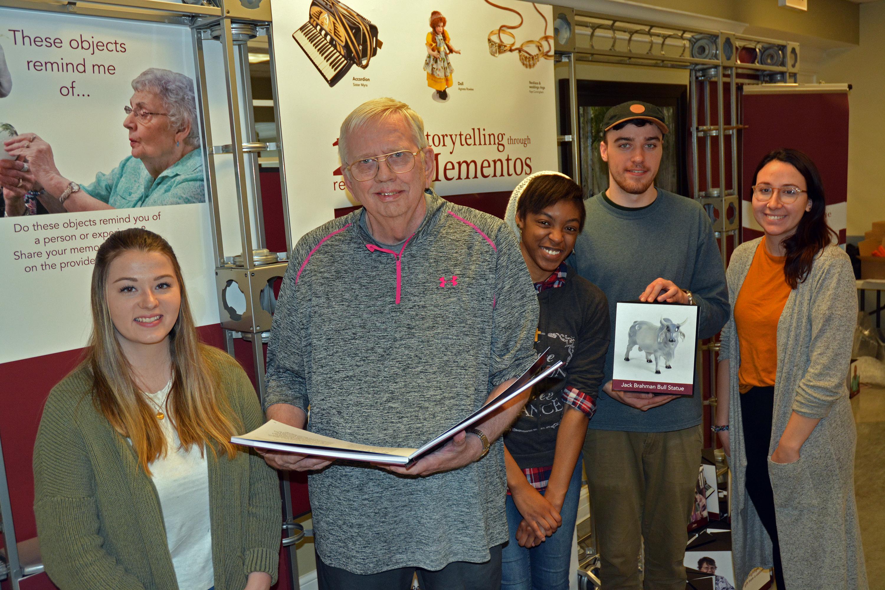 Students and a senior citizen with items from Recollections art exhibition