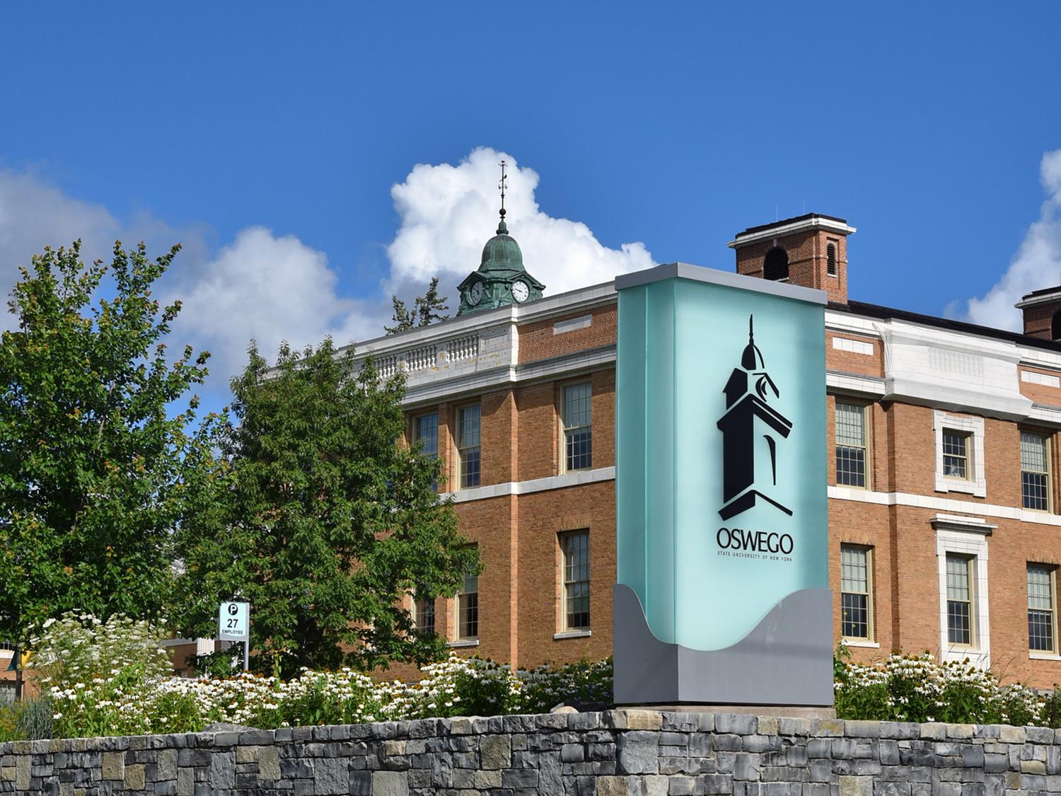 SUNY Oswego sign with background of Sheldon Hall