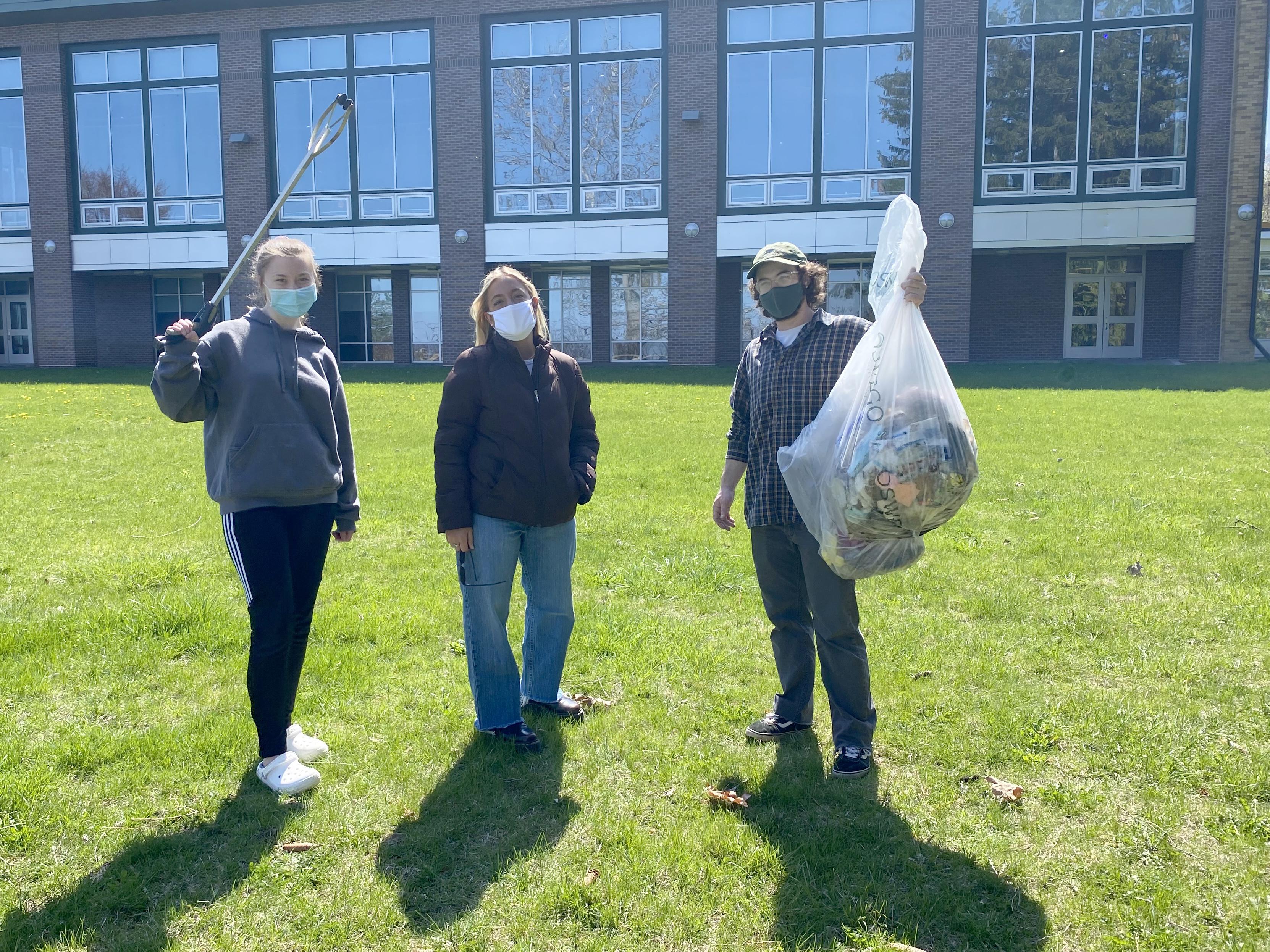 Three students show off some of what they've cleaned up as part of a campus effort