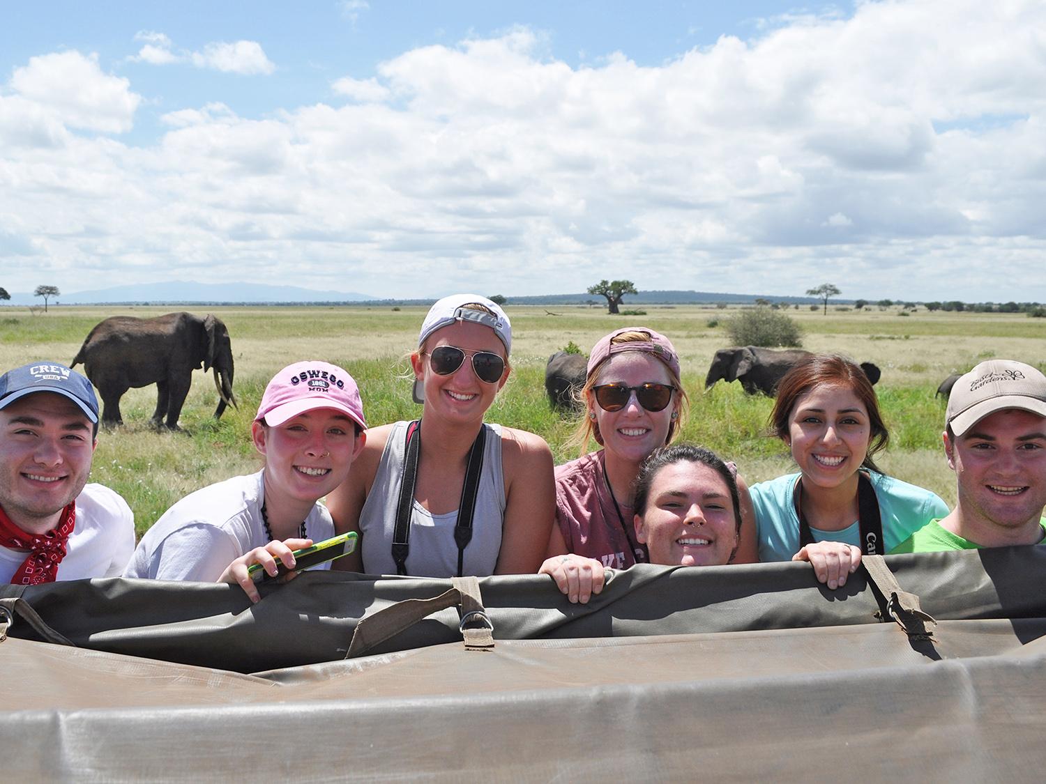 Students pose with elephants in background
