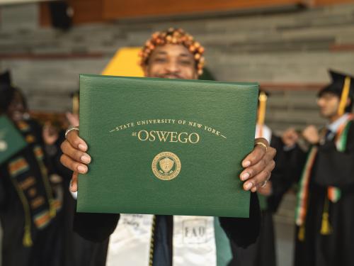 student holding up a diploma in front of other graduates
