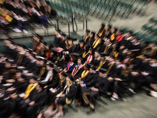 commencement photo of students sitting in their chairs that is half blurred 