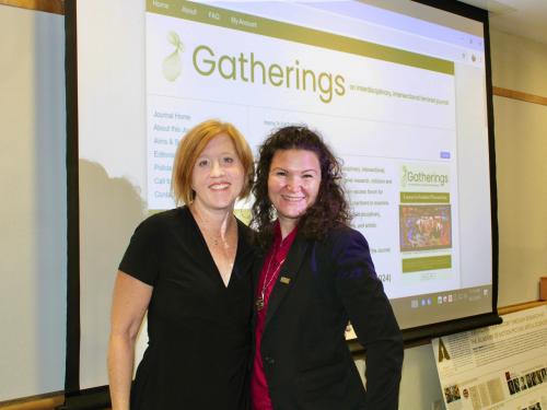 Cinema and Screen Studies professor Dr. Amy shore and English and Latin American studies studies professor Dr. Roberta Hurtado stand in front of the website for "Gatherings: An interdisciplinary and intersectional feminist journal."