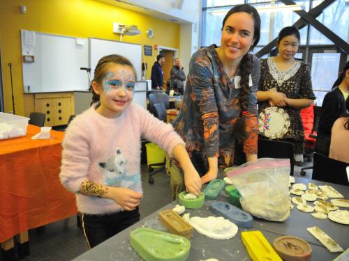 Rice Creek visitor Lexie Prosser works with the field station's Kristen Hansen to make clay animal tracks at a preview Celebrate Snow
