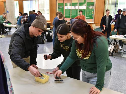 Three students work on an electromagnetism competition at a previous Engineering Week