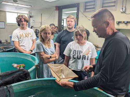 Students from SUNY Oswego and Cortland look at fish being reared to restock the region