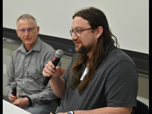 Kenny Roffo, a 2017 SUNY Oswego graduate whose accomplishments since included working on the InSight rover that landed on Mars for NASA, speaks to a full house as electrical and computer engineering faculty member Adrian Ieta looks on.