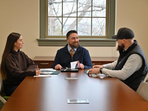 Ken Cisson meets with two students who came to SUNY Oswego after serving in the U.S. Air Force
