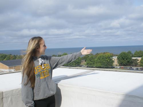 Student tour guide gestures and lake and campus