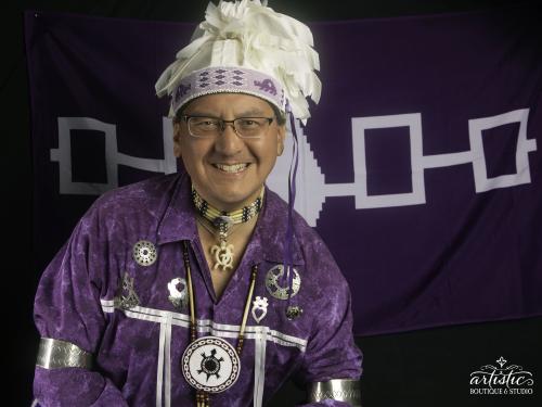 Storytellers Perry Ground stands in front of the Haudenosaunee flag