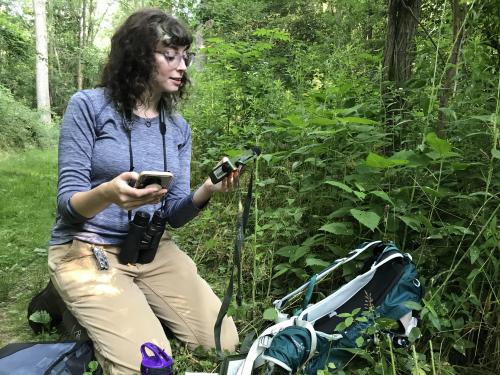 Junior zoology major Brooke Goodman checks on some automatic recording units in Rice Creek Field Station in summer 2021, part of an ongoing study on how human noise pollution impacts birds' song repertoires
