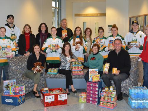 Hockey players, Oswego employees, and representatives of United Way and Human Concerns Center with food and toys