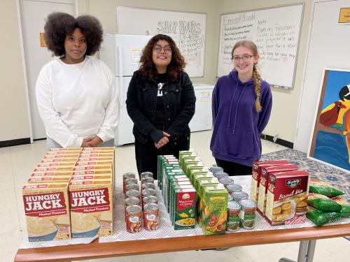 Showing some contributions to SHOP's food drive are student volunteer Issagha Bah; April Lopez, assistant dean of students, basic needs case manager and homeless liaison for the Office of the Dean of Students; and student volunteer Alexis Chainao.