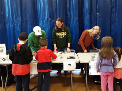 SUNY Oswego students Daniel Thomas, Hugh Riley Randall and Layla Sprague help elementary school students with a STEAM activity