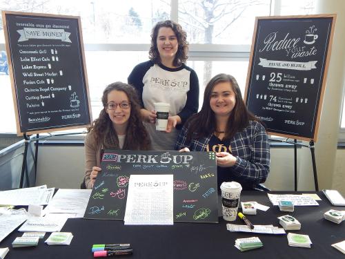 Students showing off Perk Up program to promote refillable coffee mugs