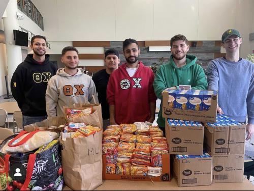 Theta Chi brothers pose with their large amount of donations to the Students Helping Oz Peers pantry