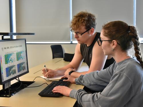 Tom White and Zoe Bush, who just earned their meteorology degrees in May, look over data from their research with Climavision related to gap-filling radar