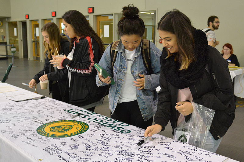 Students sign Class of 2017 banner at Grad Fair