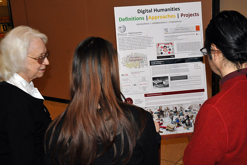 Faculty read posters at College of Liberal Arts and Sciences interdisciplinary collaboration event