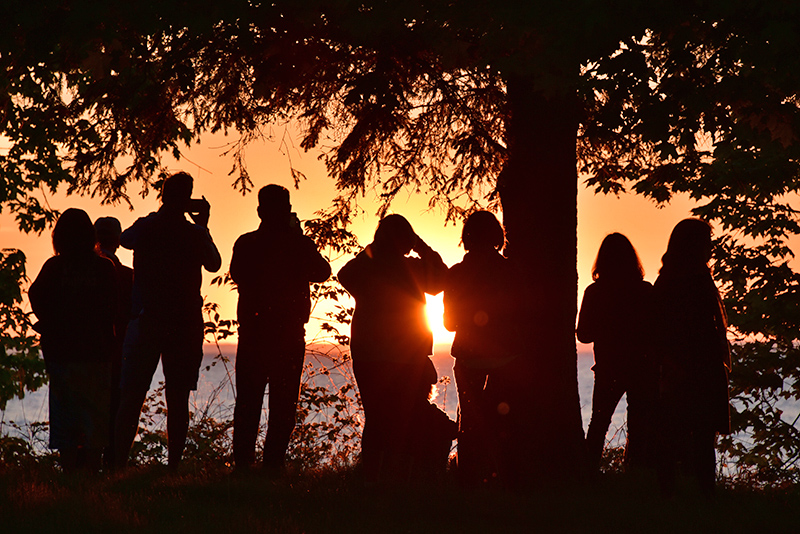 Alumni take photos of sunset over Lake Ontario