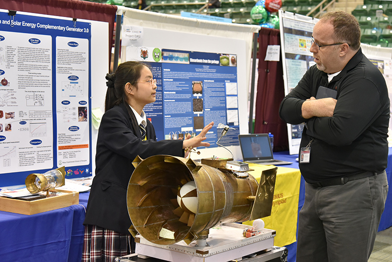 Fengyun Chen, a student from China, explains her project using wind force pressurization with complementary solar energy to generate electricity