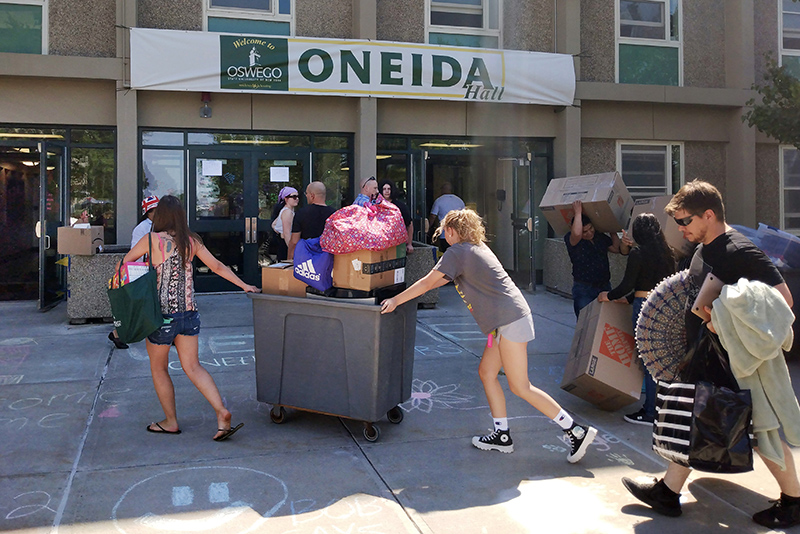 Students and parents utilize a moving cart outside of Oneida Hall during move-in week.