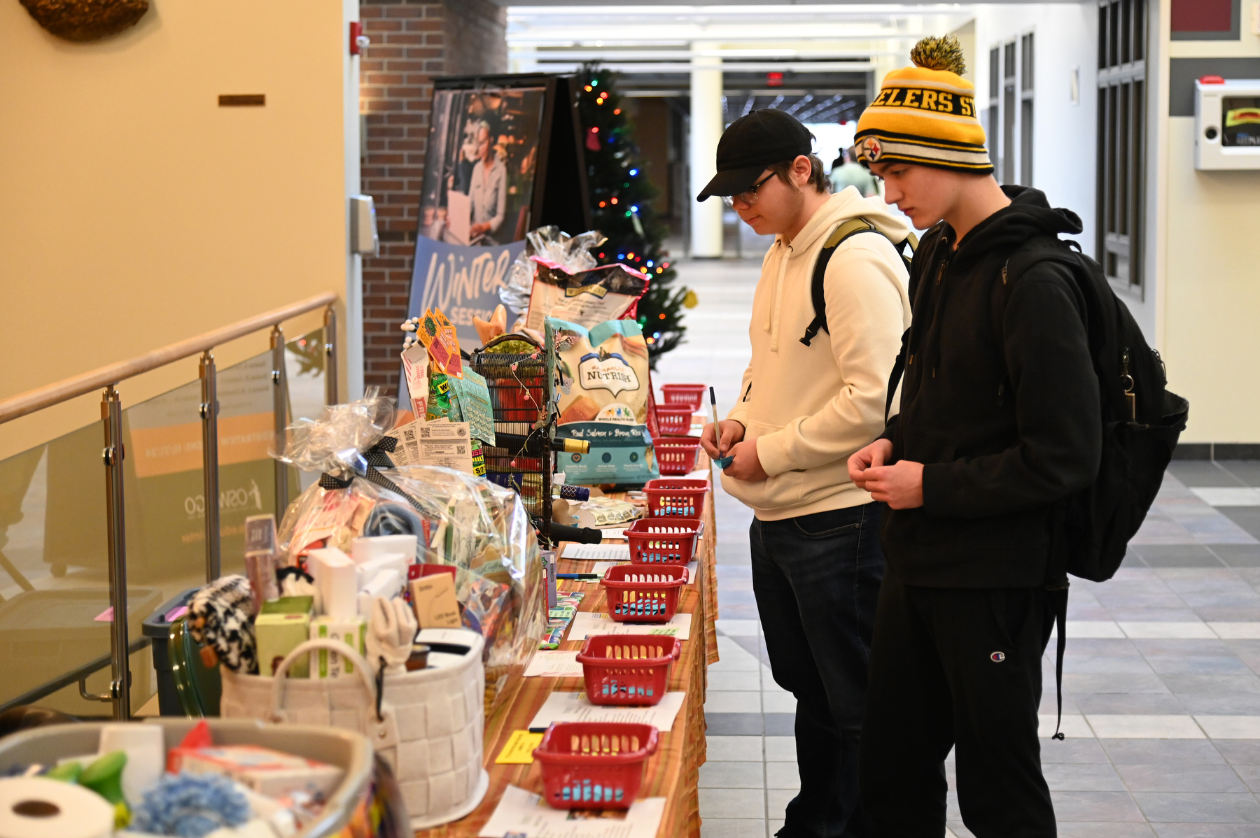 SUNY Oswego’s State Employees Federated Appeal (SEFA) "Baskets of Caring" fundraising campaign held Nov. 20 and 21 supports the United Way of Greater Oswego County. Pictured are Quinn Murphy (left), a sophomore business major, and Jason Szakacs, a freshman broadcasting major, making donations by casting their "votes" for some of the gift baskets in Marano Campus Center.