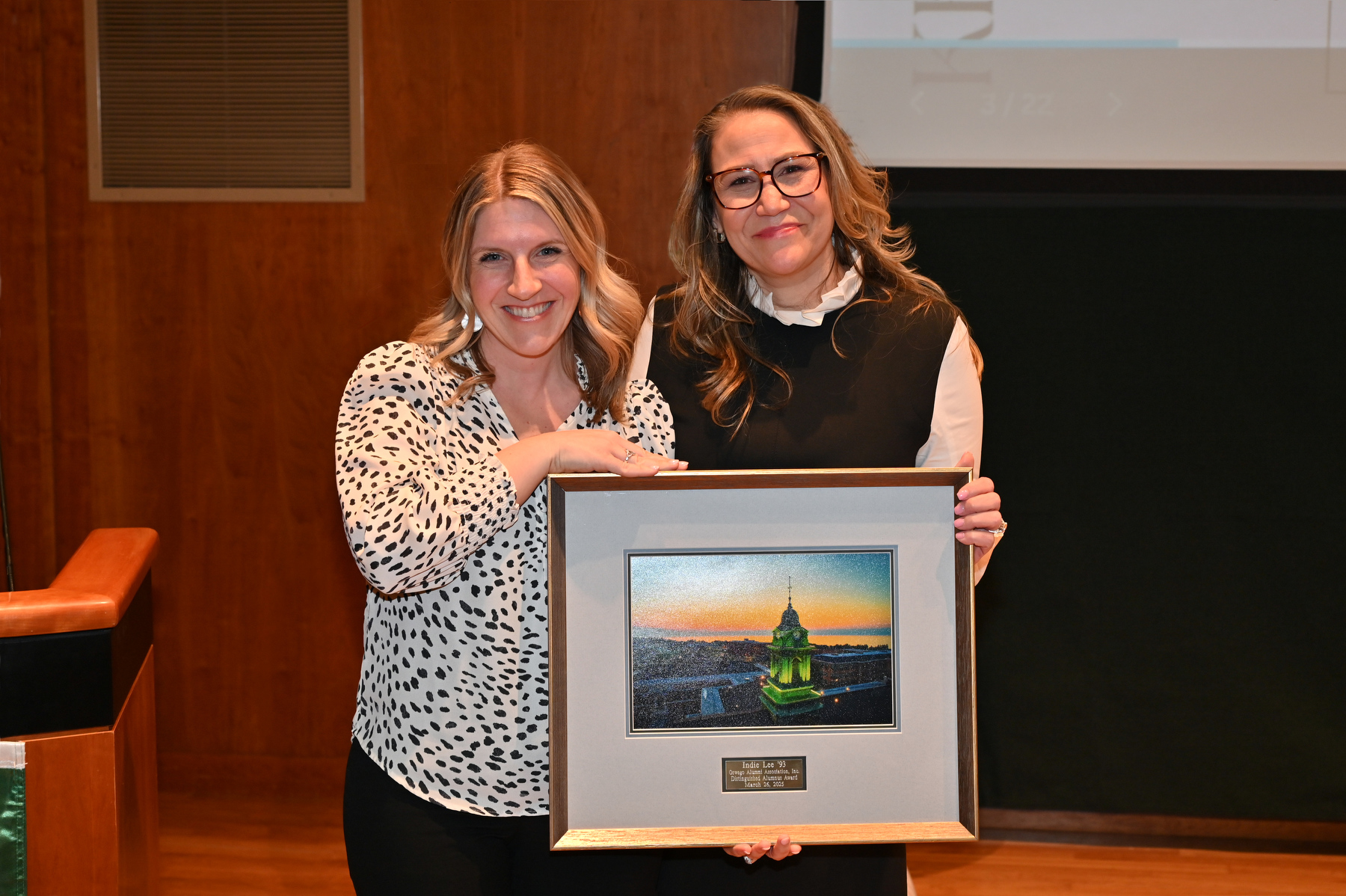 Indie Lee aka Lisa Swengros Agona (right), a 1993 graduate, received the Distinguished Alumna Award during the Women’s Empowerment Summit held March 26. Presentin  the award is Laura Kelly '09, executive director of the Oswego Alumni Association and director of alumni engagement.