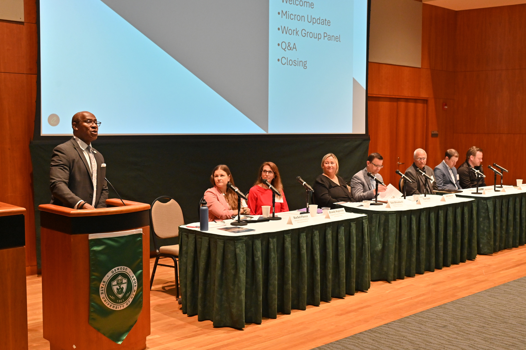 The Oswego County Micron Strategy Steering Committee hosted its second annual summit June 20, at SUNY Oswego’s Marano Campus Center auditorium, celebrating a year of significant milestones and strategic collaboration supporting Micron Technology’s historic $100 billion investment in Central New York. President Peter O. Nwosu (at podium) welcomes subcommittee chairs (seated) and attendees to the summit.