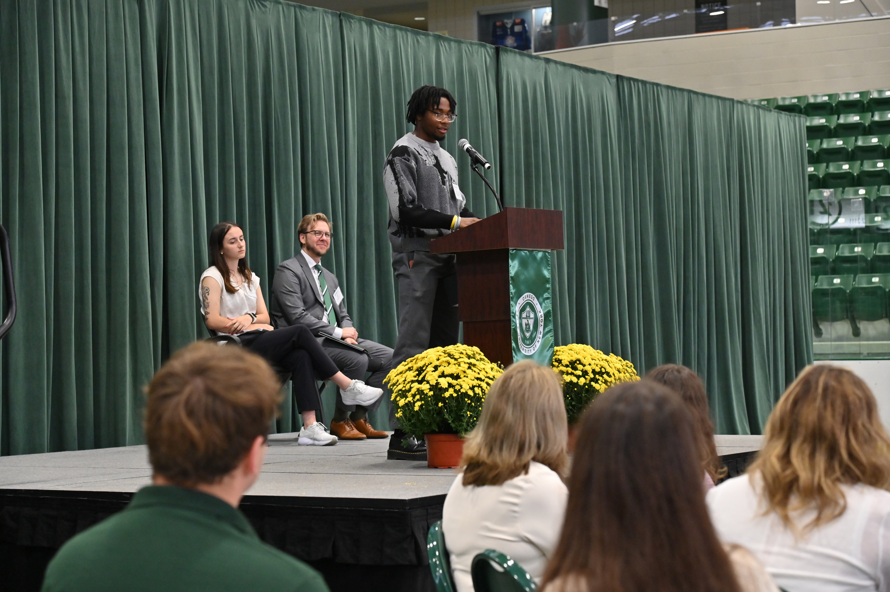 The annual Scholars Brunch, a celebratory gathering of scholarship donors and recipients, was held on Saturday, Sept. 27. Remarks for the event were provided by scholarship recipients Daniel Mars '26 (pictured at podium) and Ayla Snyder '28 (seated left), scholarship benefactor and alumna Christie Sommers '73, and President Peter O. Nwosu. Vice President Heath Wood (seated, center) served as emcee for the event held in the Deborah F. Stanley Arena and Convocation Hall.