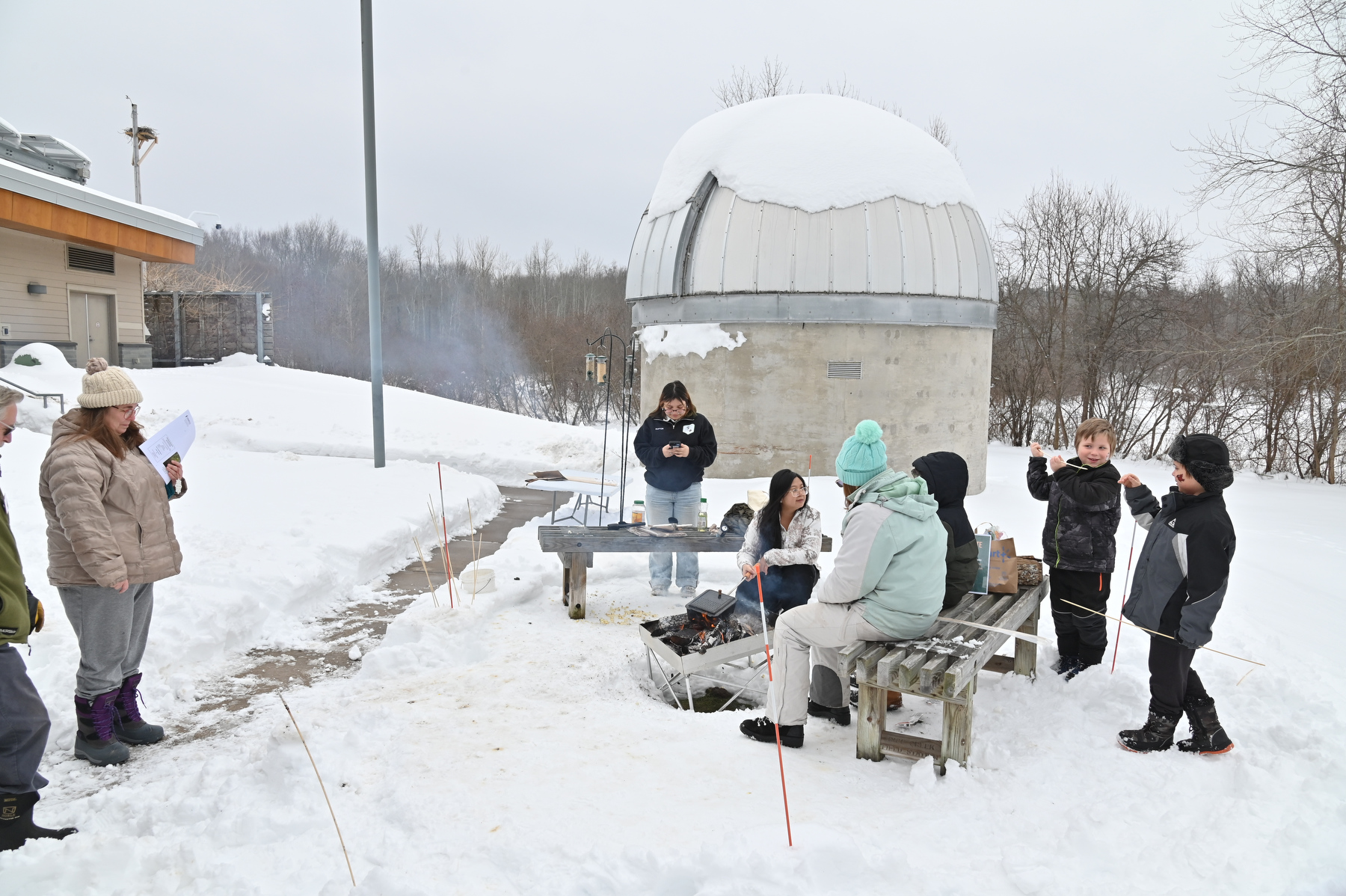 Rice Creek Field Station's annual Celebrate Snow Winter Festival included such family-friendly activities as guests roasting marshmallows and s'mores over a campfire. In the background is the campus observatory.