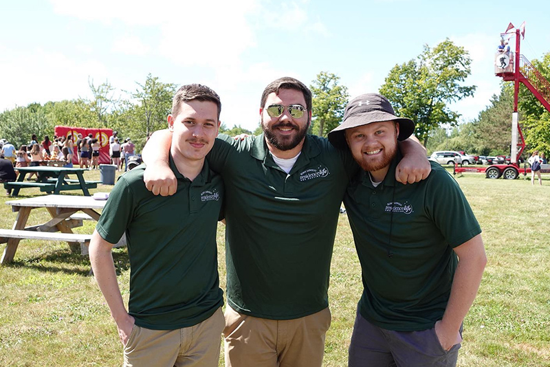 Residence Life and Housing staff enjoy LakerFest on Saturday, August 27 at SUNY Oswego. All three are wearing matching hunter green polos.