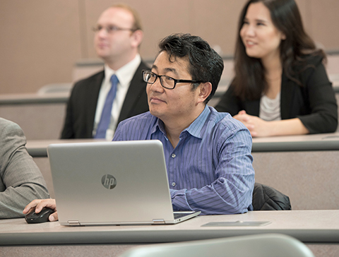 Business students in a classroom listen attentively