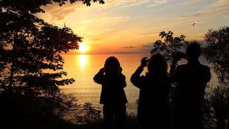 Sunset photo by Jennifer Broderick 3 silhouettes of people taking photos of the Oswego sunset